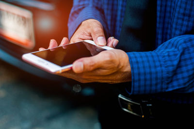 Midsection of man holding mobile phone