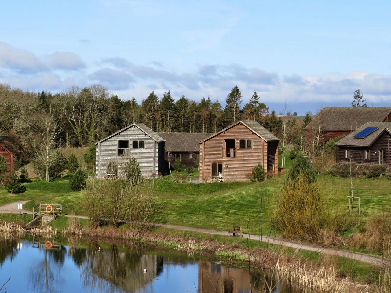 building exterior, architecture, reflection, tree, water, built structure, sky, house, green color, grass, lake, waterfront, growth, tranquil scene, tranquility, nature, rural scene, cloud - sky, day, beauty in nature