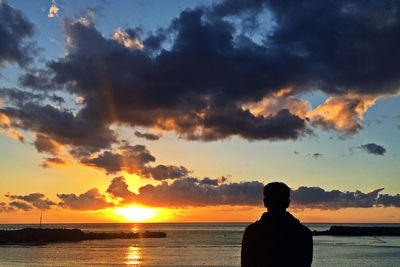 Silhouette man looking at sea against sky during sunset