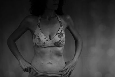 Midsection of young woman standing against gray background