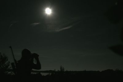 Silhouette of woman against sky at night