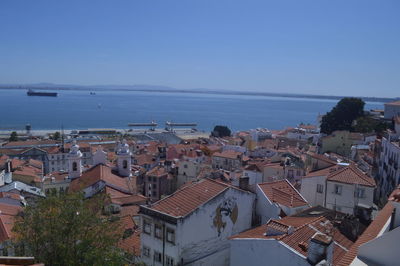 High angle view of town by sea against clear sky