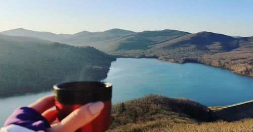 Midsection of man drinking glass with mountains in background