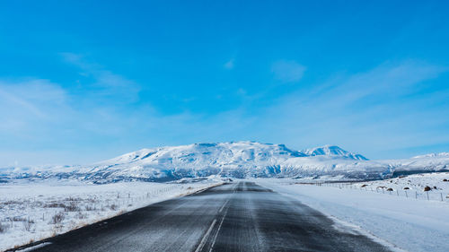 Road amidst snowcapped mountains against sky