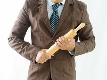 Midsection of man holding umbrella against white background