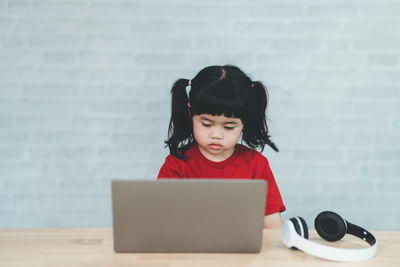 Portrait of young woman using digital tablet while sitting on table