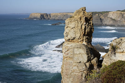 Rock formation by sea against sky