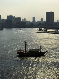 Boat sailing on sea by city against sky
