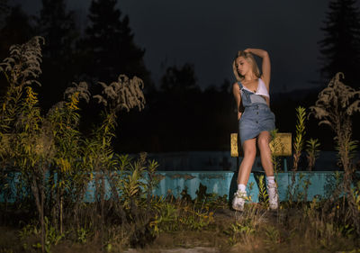 Full length of young woman looking away at night