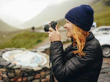 Woman photographing three sisters of glencoe, on a wet day