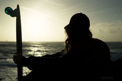 Silhouette woman on beach against sky during sunset