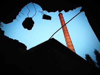 Low angle view of silhouette trees against blue sky