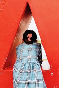 Full length of woman standing against red wall