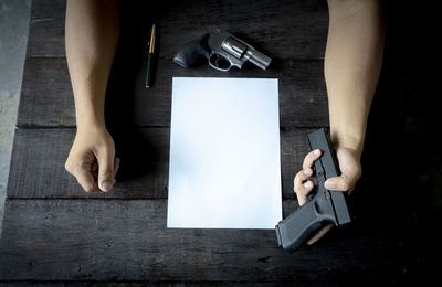 Close-up of businessman with gun and paper on table 