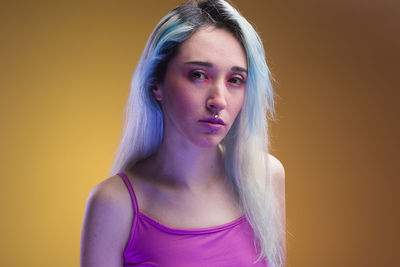 Portrait of young woman against yellow background