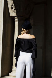 Rear view of woman wearing off shoulder top while entering historic building