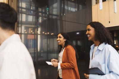 Smiling businesswoman walking with female delegate during seminar at convention center