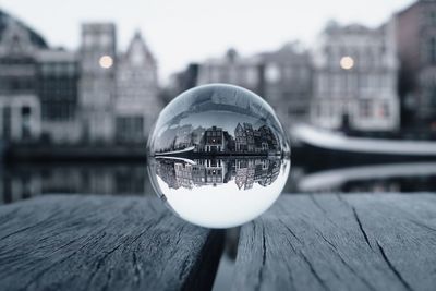 Close-up of crystal ball on water against buildings in city