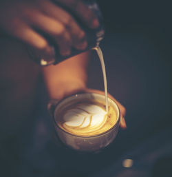 Close-up of hand holding coffee cup over black background