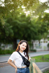 Young woman standing against trees