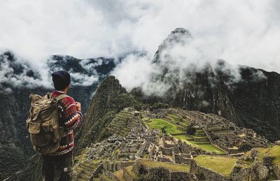 Rear view of man standing on mountain against sky