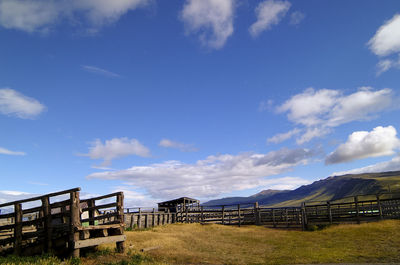 Fence on field against blue sky