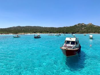 Boats sailing in sea against clear sky