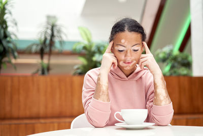 Portrait of woman with coffee cup sitting on table