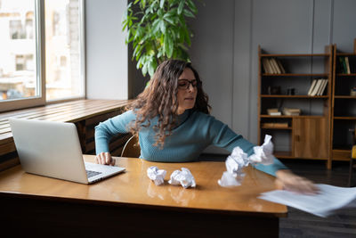 Hysterical woman throwing crumpled paper documents away suffer from breakdown, burnout and overwork