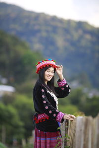 Portrait of woman standing against railing