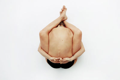 Midsection of shirtless woman against white background