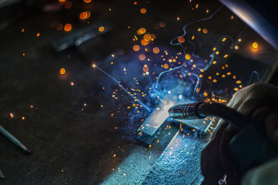 Midsection of man holding illuminated lighting equipment at night