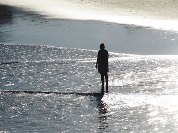 Rear view of man standing in sea against sky