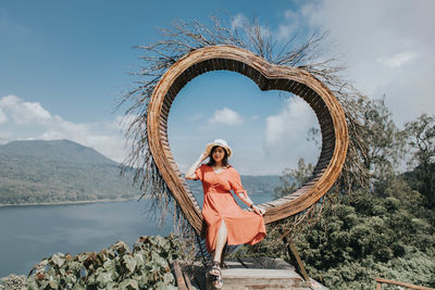 Pretty asian woman is sitting on straw nest, wanagiri hidden hill, bali.