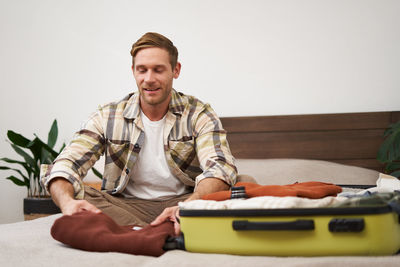 Portrait of young man sitting on bed at home