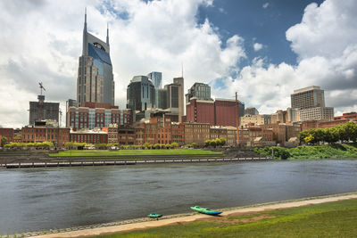 Buildings by river against sky in city