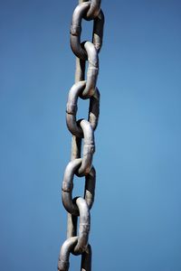 Low angle view of chain against clear blue sky