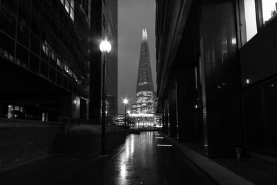 Illuminated street amidst buildings in city at night