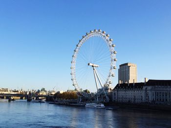 Ferris wheel in city against clear blue sky