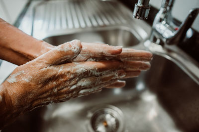 Cropped image of man washing hands in sink