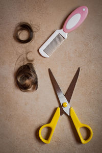 Directly above shot of scissors with comb and hair on floor