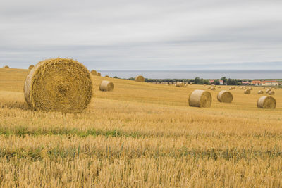 Hay bales on field against sky