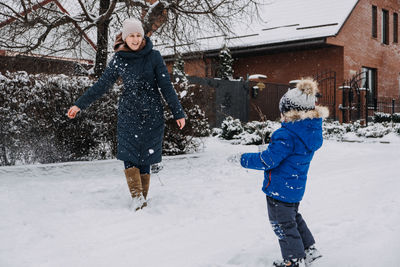 Outdoor family activities for happy winter holidays. happy mother and two sons playing snowballs on