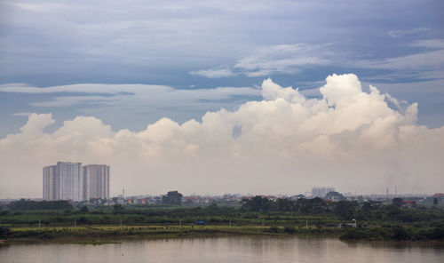 Scenic view of river by buildings against sky