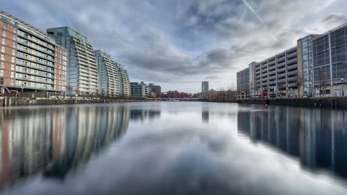 Reflection of buildings in lake against sky in city