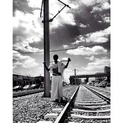 Man standing by railroad tracks against sky