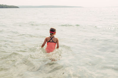 Girl swimming in sea against sky