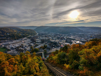 High angle view of incline tracks by city with mountains against sky