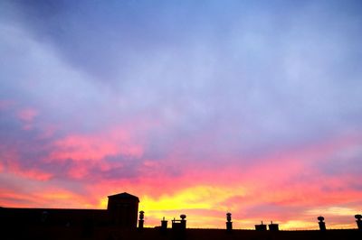 Low angle view of silhouette buildings against cloudy sky