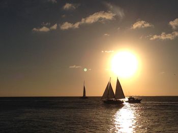 Silhouette sailboat sailing on sea against sky during sunset